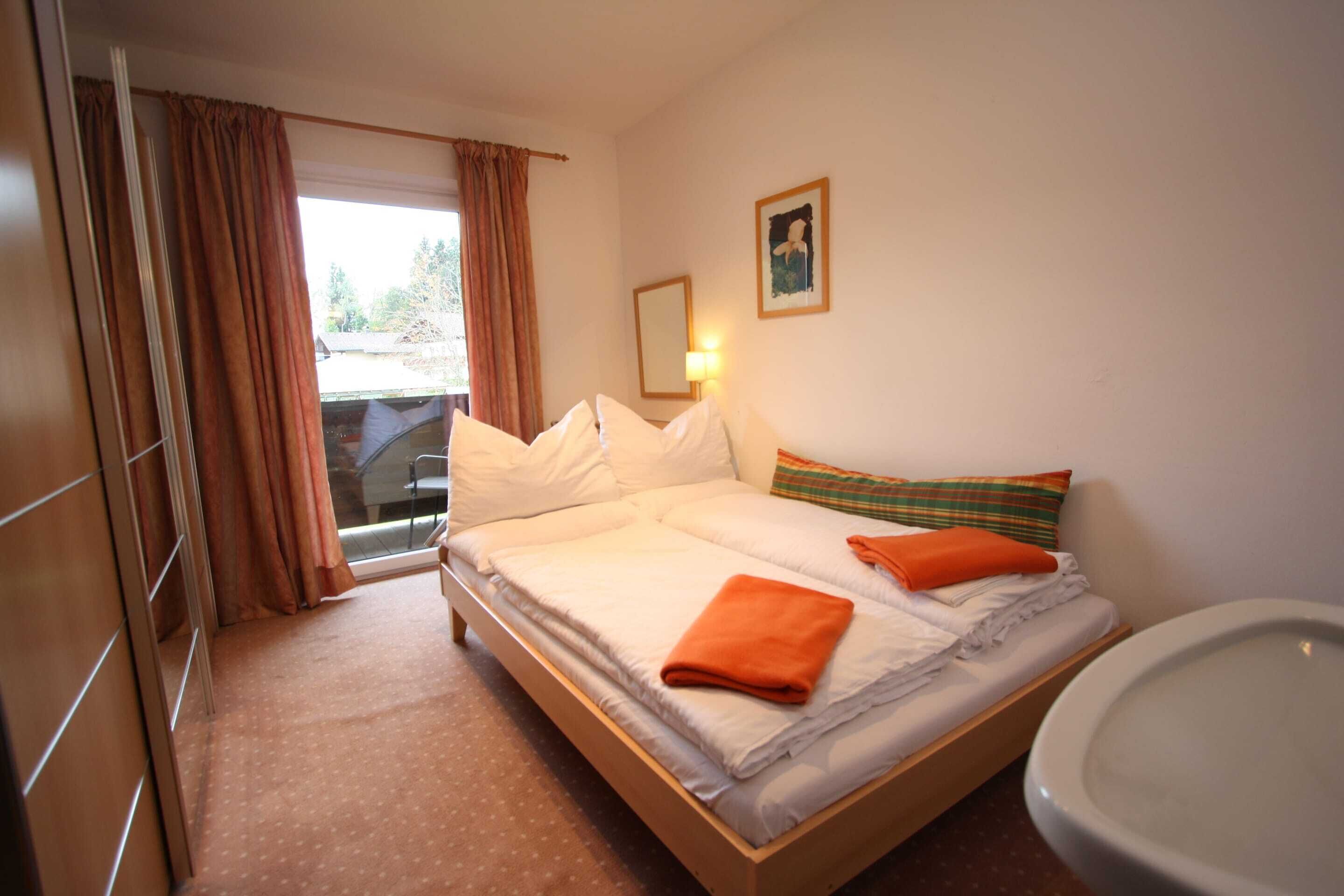 Een hotelkamer met een bed, een badkamer, een raam met gordijnen en een spiegel aan de muur.