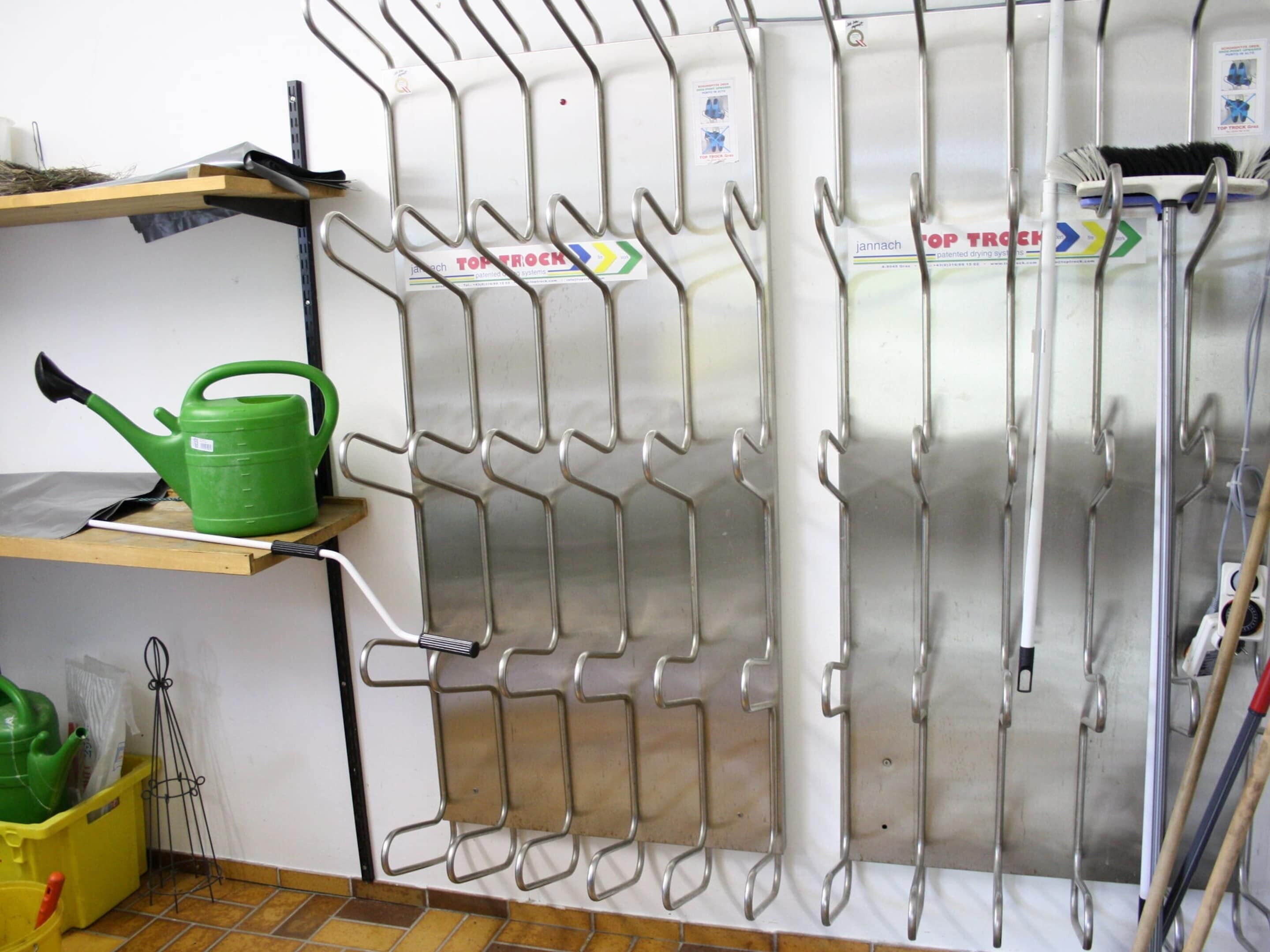 Una cocina con un estante metálico que contiene varios utensilios, un regador verde y un contenedor amarillo.