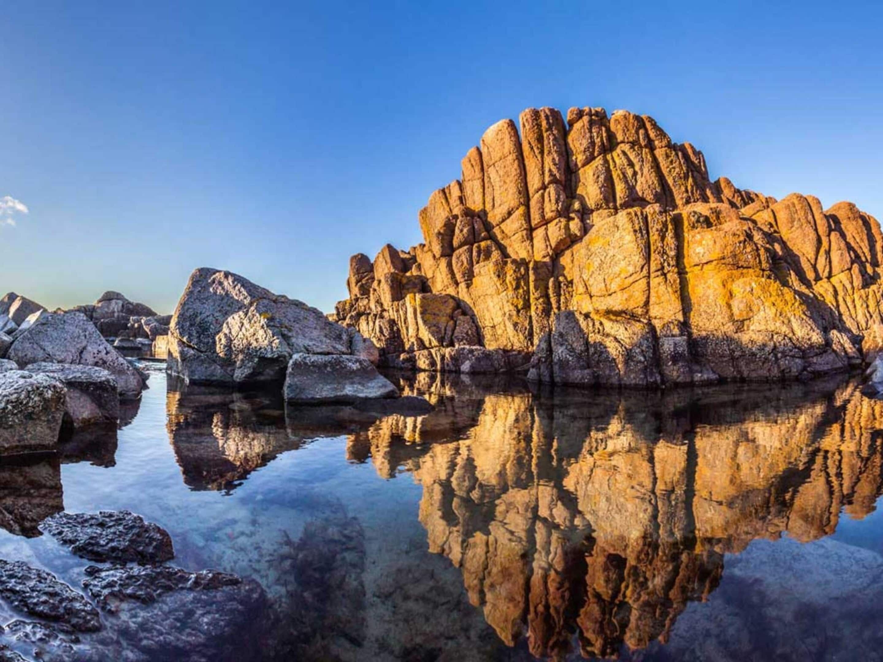 A rocky landscape with clear reflections in calm water.