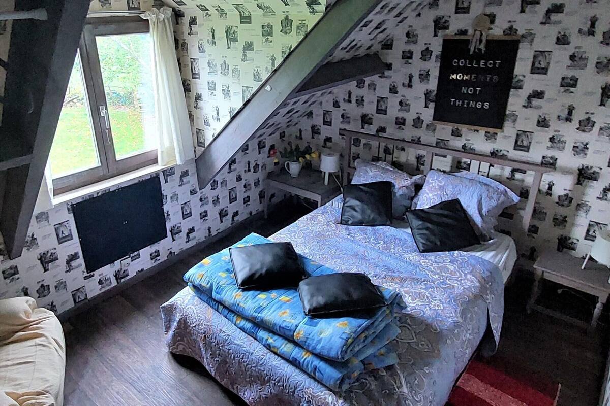 Ein Schlafzimmer mit Bett, einer Couch, einem Fenster und einer Wand mit der Aufschrift 'COLLECT MOMENTS NOT THINGS'.