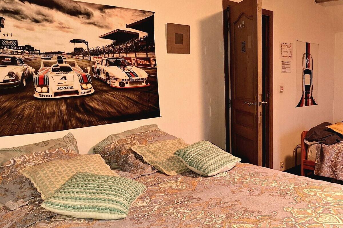 Ein Schlafzimmer mit zwei Betten, einem großen Rennsportposter und einem kleineren Auto-Poster an der Wand.