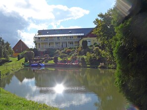 Ein Hotel mit einem großen Gebäude, einem Teich und umliegender Bepflanzung.