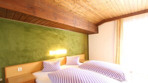 A hotel room with a wooden ceiling, a green accent wall, a bed with striped bedding, and a nightstand. - Spacious Apartment Near Ski Area in Mittersill (Mittersill)