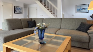Un salon avec un canapé, une table basse en verre et un escalier.