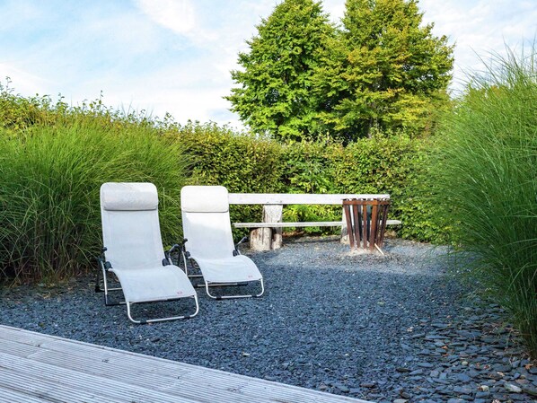 A gravel path with two white lounge chairs and a wooden bench. - Boutique Chalet in Bullingen Near Lake (Buellingen)