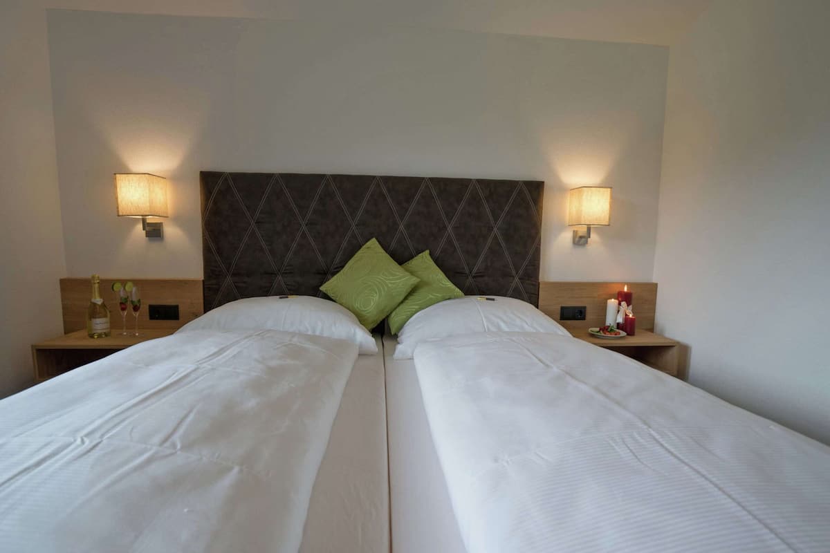 A double bed with a dark headboard and two bedside tables, each with a lamp and a bottle of water.