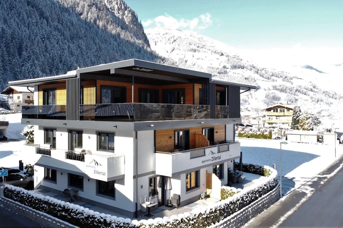A modern multi-story building with balconies, located in a snowy mountainous area.
