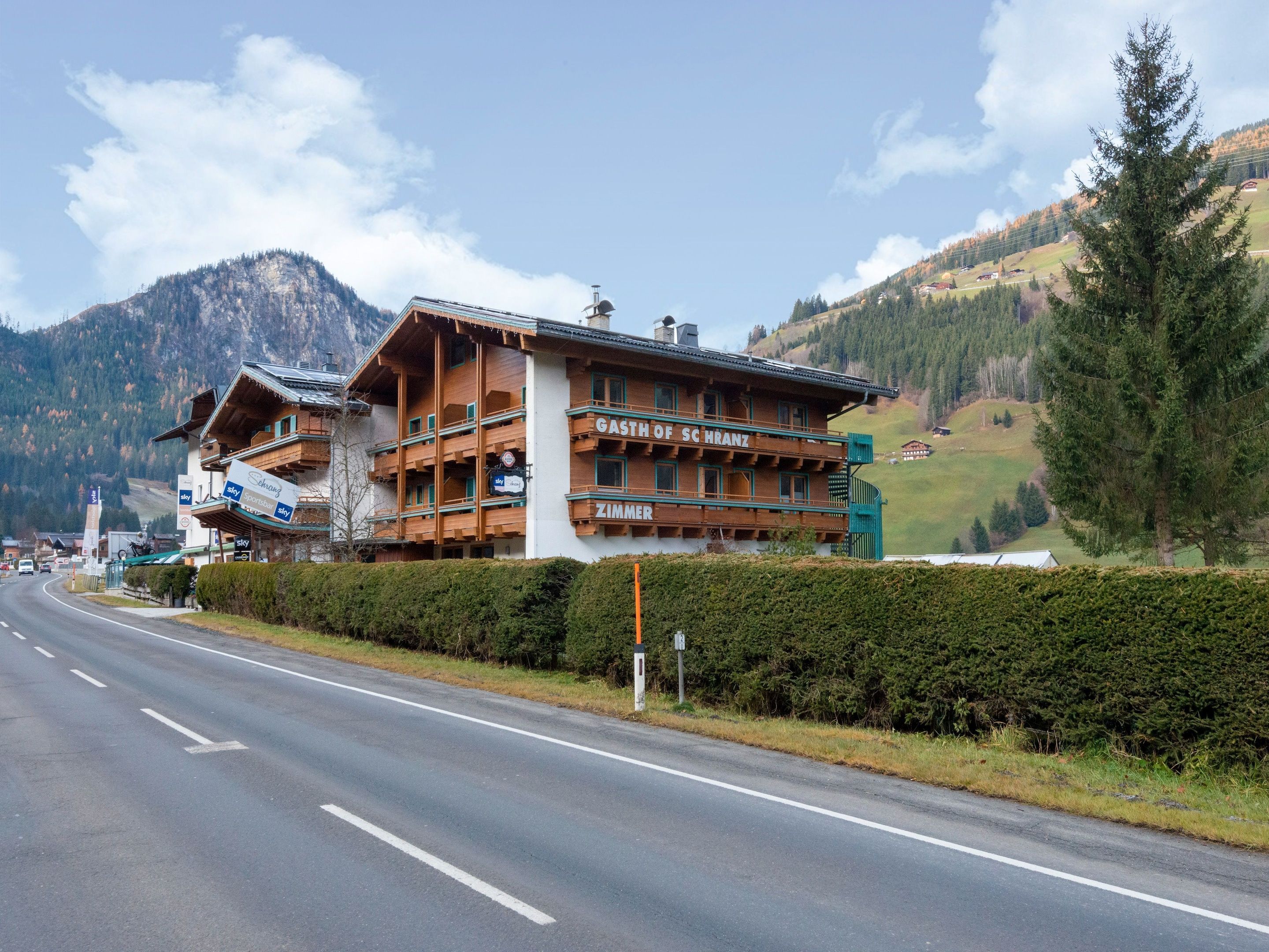 Un albergue de montaña con un letrero que dice "GASTHOF SCHRANZ" y "ZIMMER".