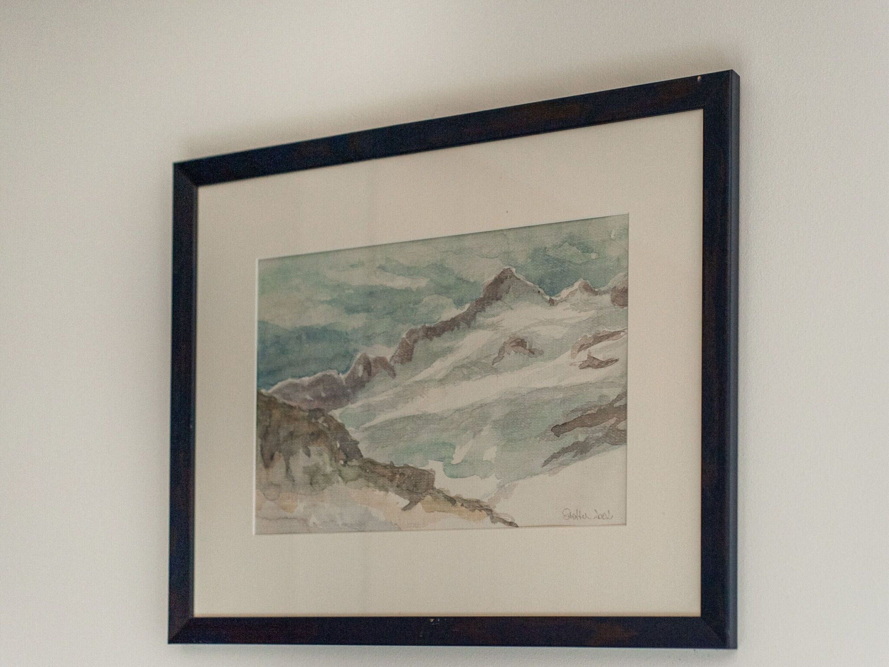 Une aquarelle représentant un paysage de montagne, encadrée.