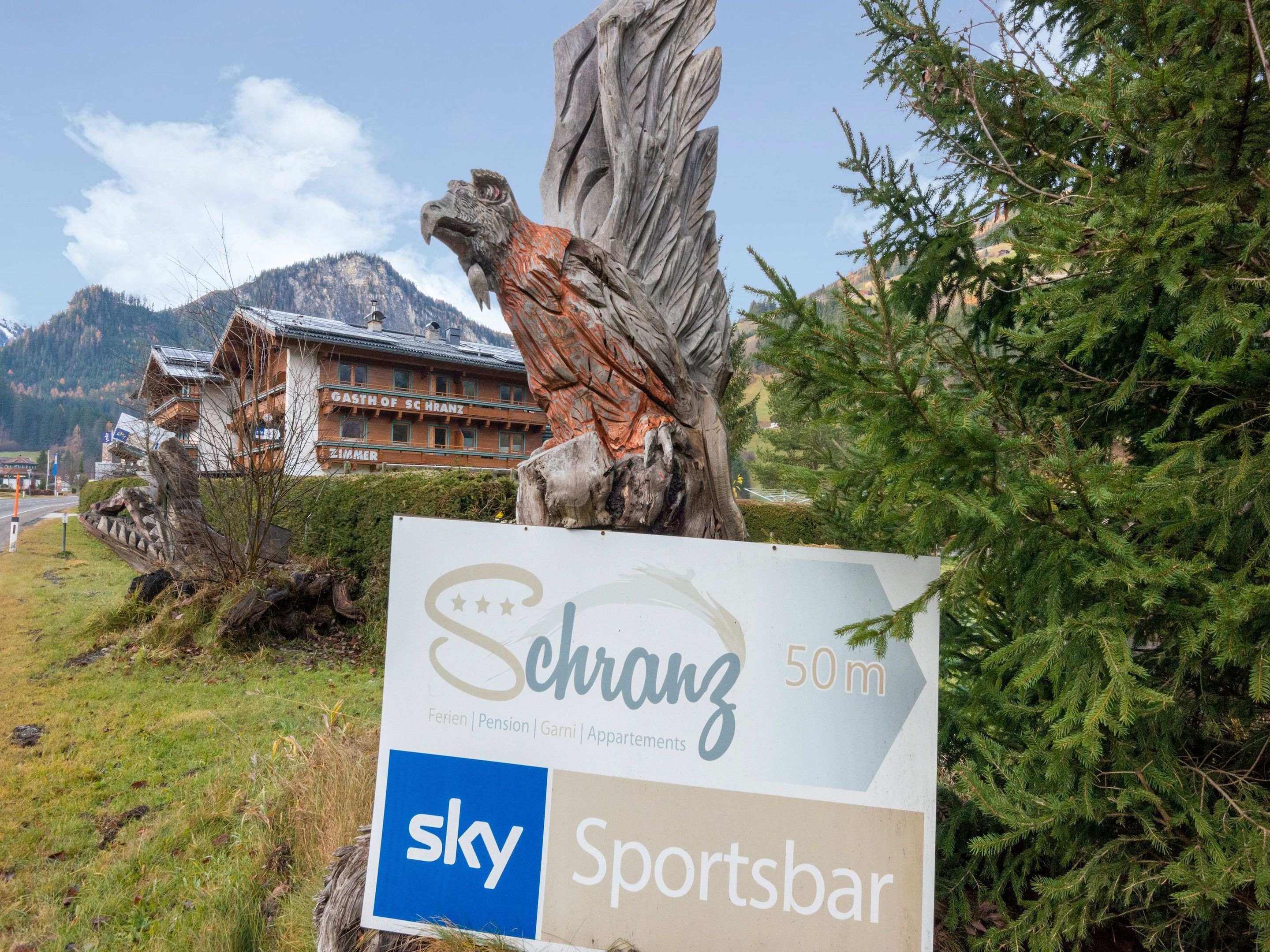 A sign for 'Schranz 50m' with amenities listed including 'Ferien', 'Pension', 'Garni', and 'Apartments'.