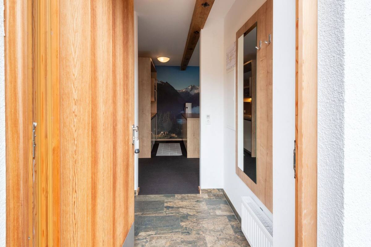 A hallway with wooden doors, a stone-tiled floor, and a mountain mural on the wall.