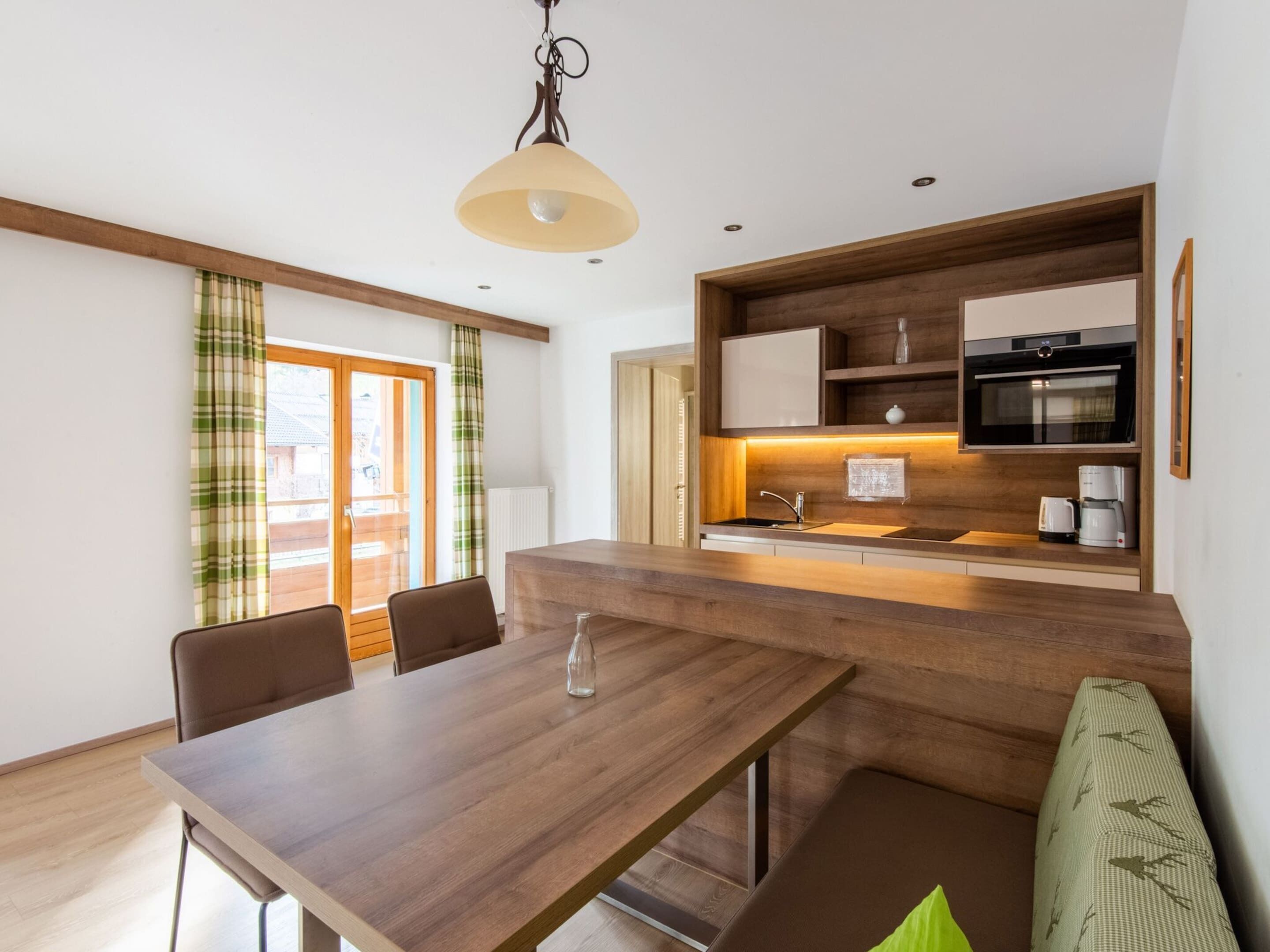 A modern kitchen with wooden cabinetry, a built-in oven, and a coffee maker.