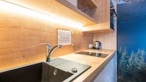 A modern kitchen with a stainless steel sink, a kettle, and a wooden countertop. - Lovely Apartment With Sauna, Ski Storage, Pool, Terrace (Wald im Pinzgau)