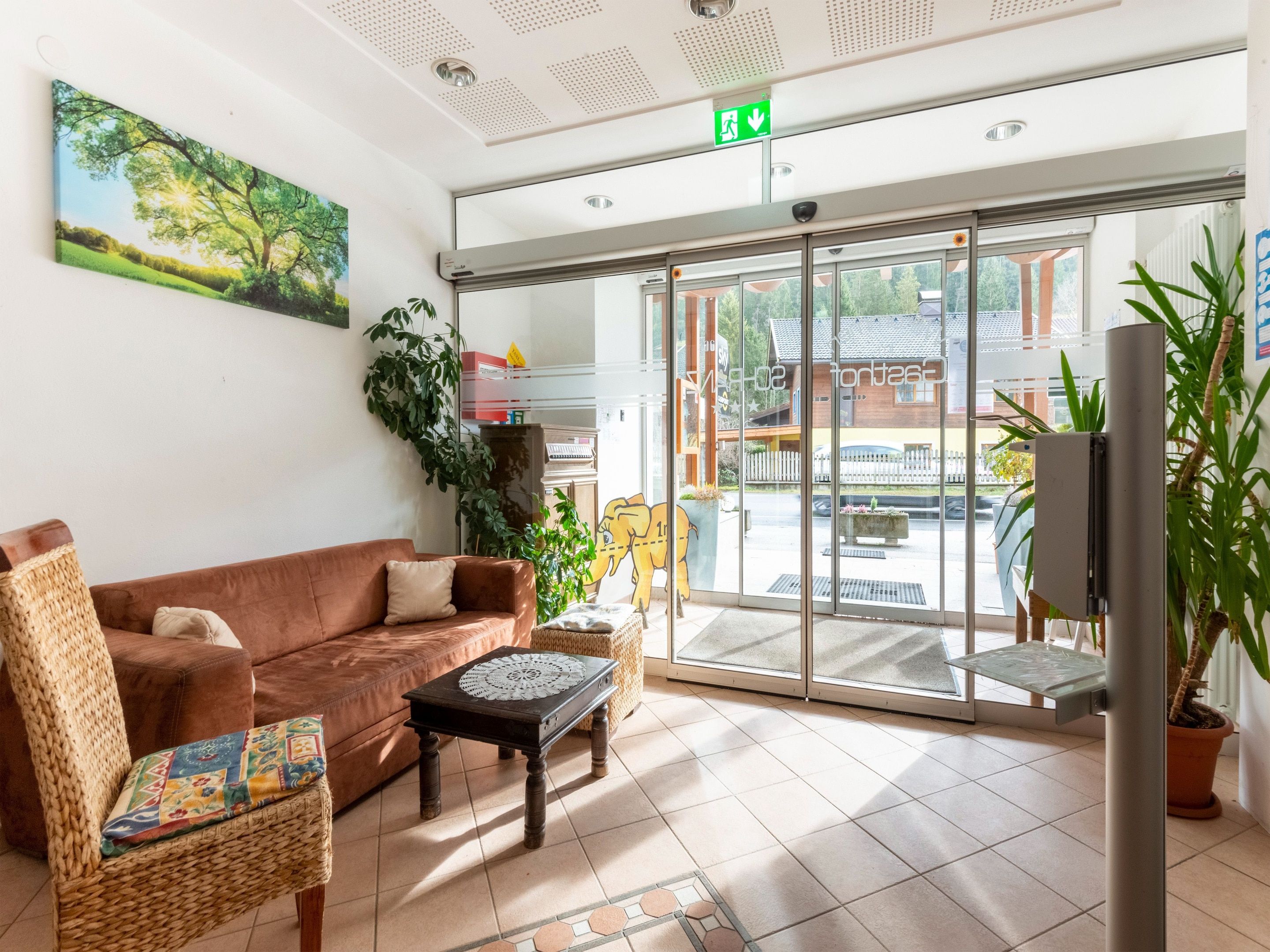 A reception area with a brown sofa, wicker chairs, a small table, and a large window with a view of the outside.