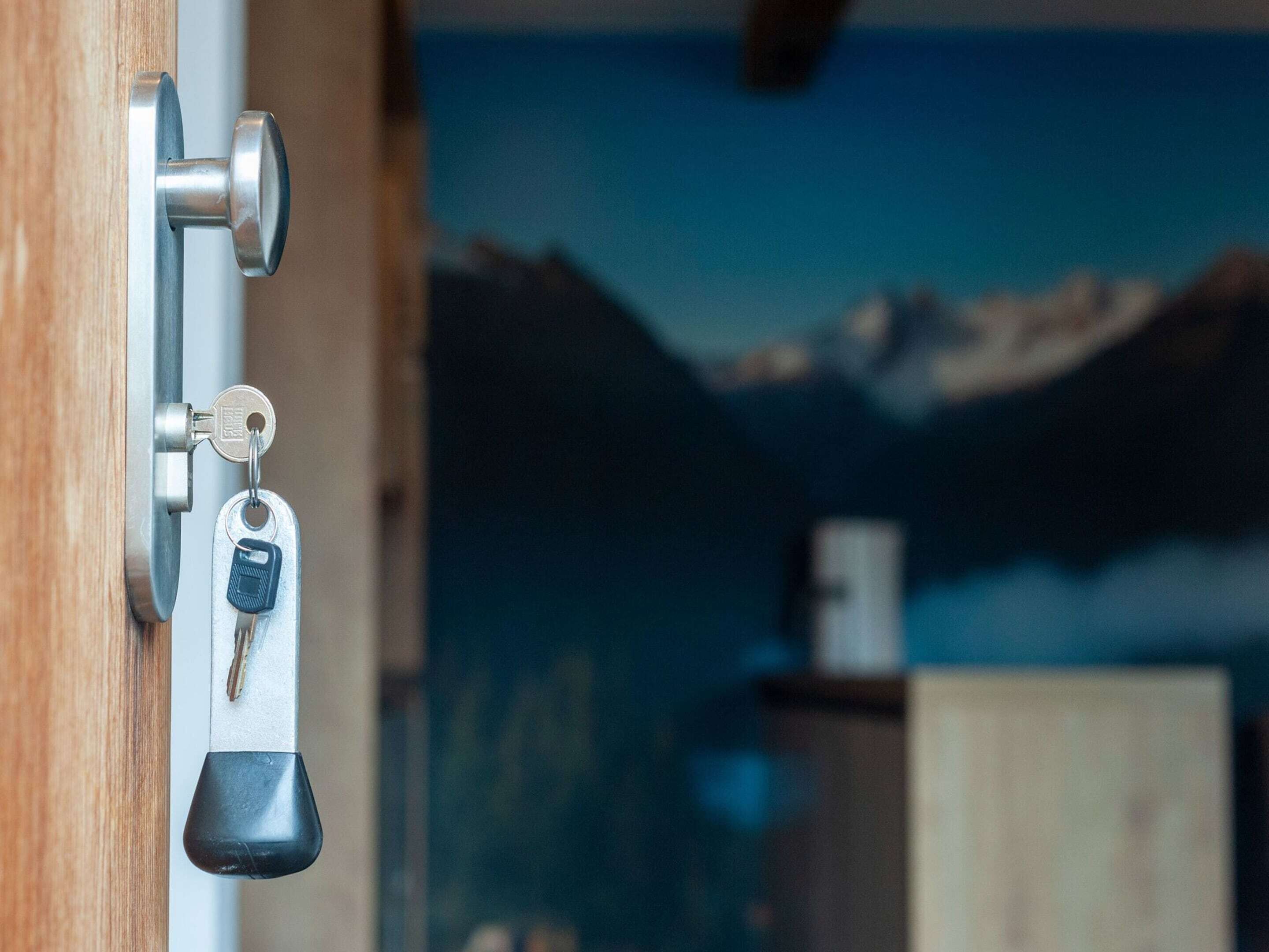 A door with a keyhole and a key, and a mountain landscape in the background.