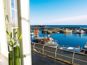 A view of a harbor with boats docked, a clear sky, and a building with a window and a green plant. - 6 Person Holiday Home in Svaneke (Svaneke)
