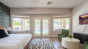 Ein geräumiges Schlafzimmer mit einem Bett, einem gemusterten Teppich, einem runden Couchtisch und einem Deckenventilator.