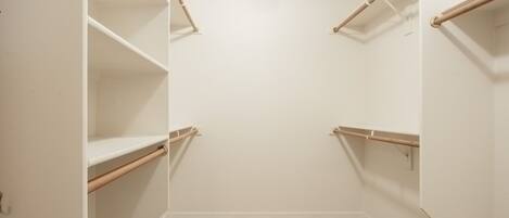 A walk-in closet with white walls and wooden flooring.