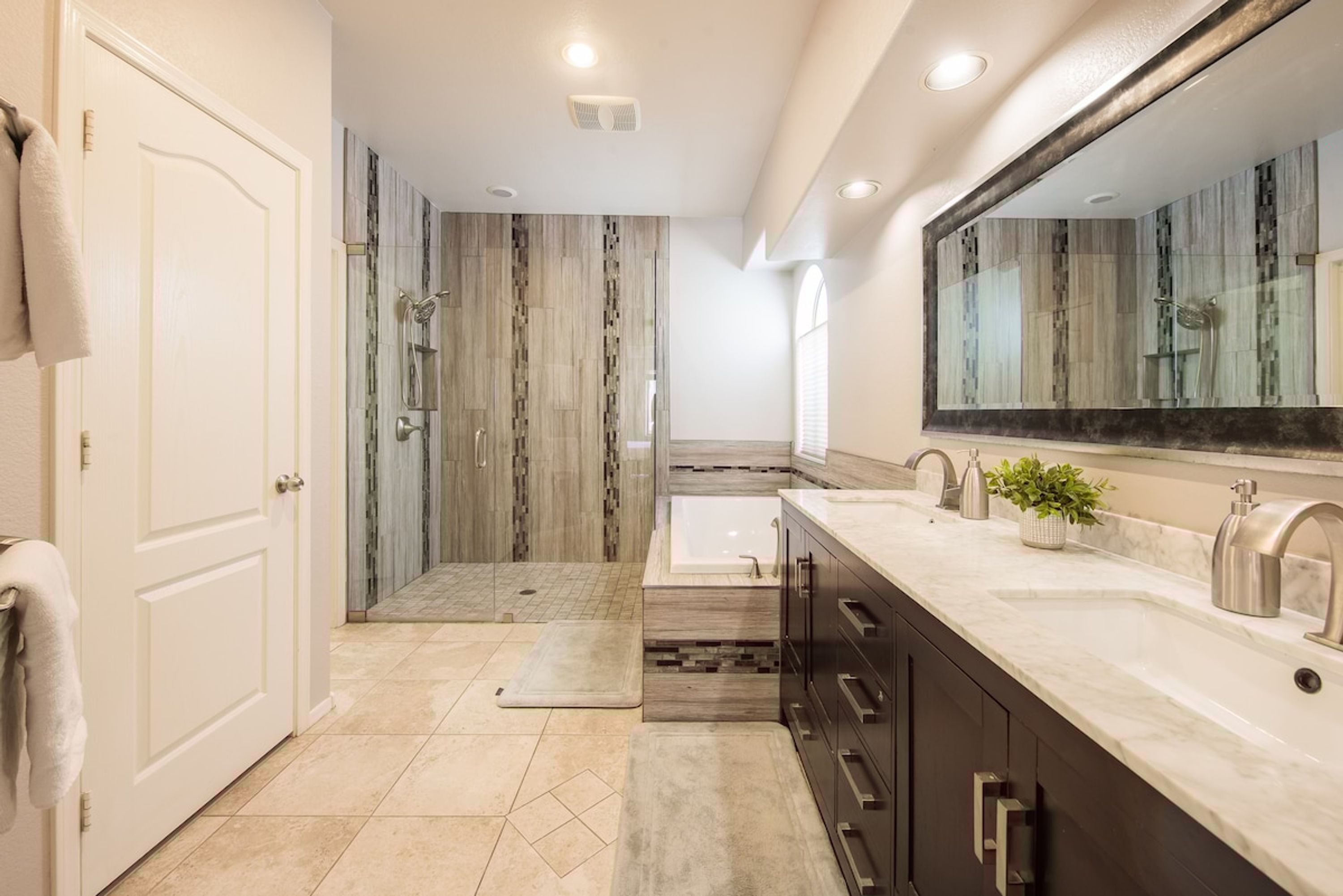 A modern bathroom with a walk-in shower, a large mirror, and a vanity with a sink.