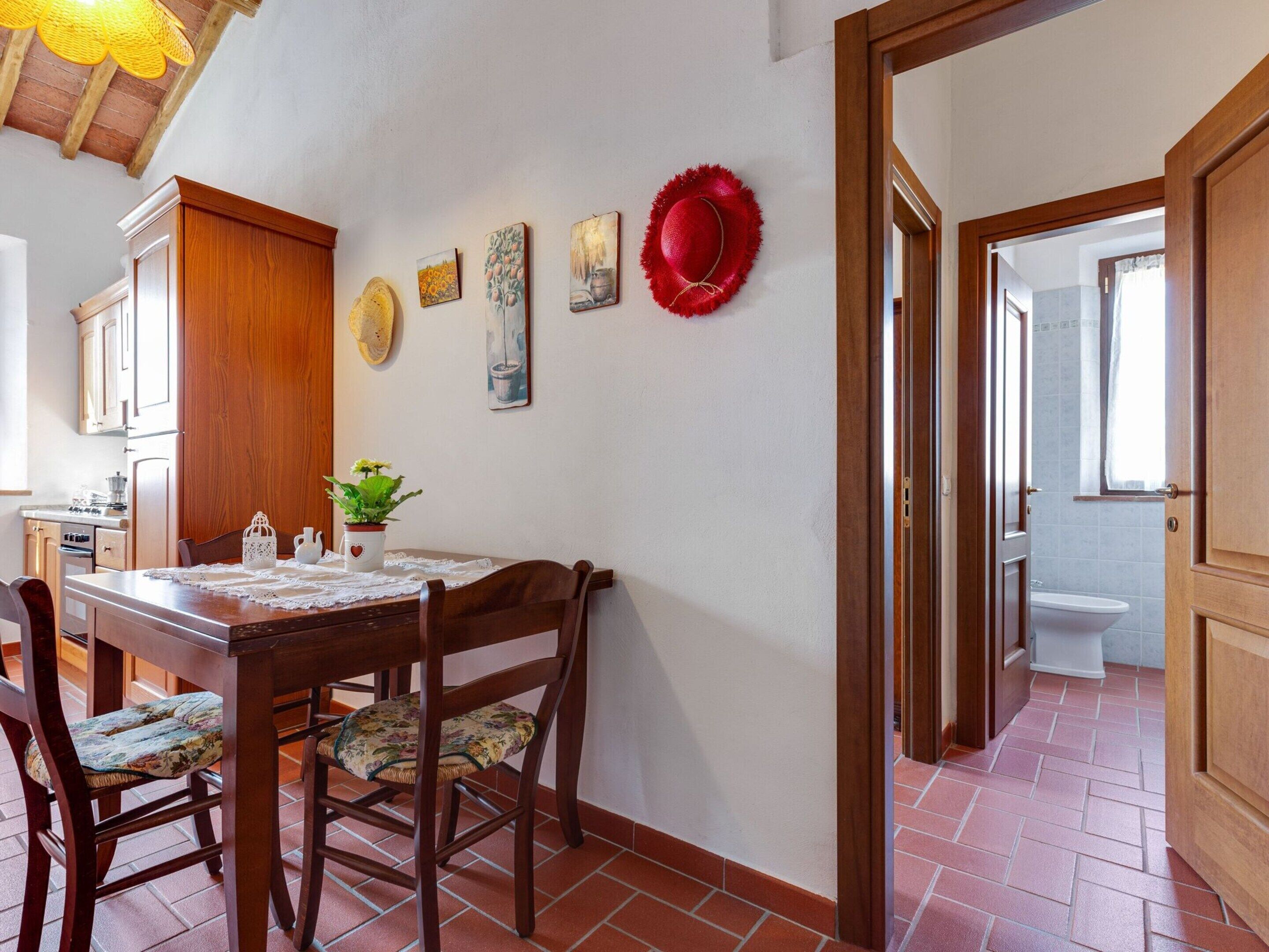 A dining area with a wooden table, chairs, and a kitchen in the background.