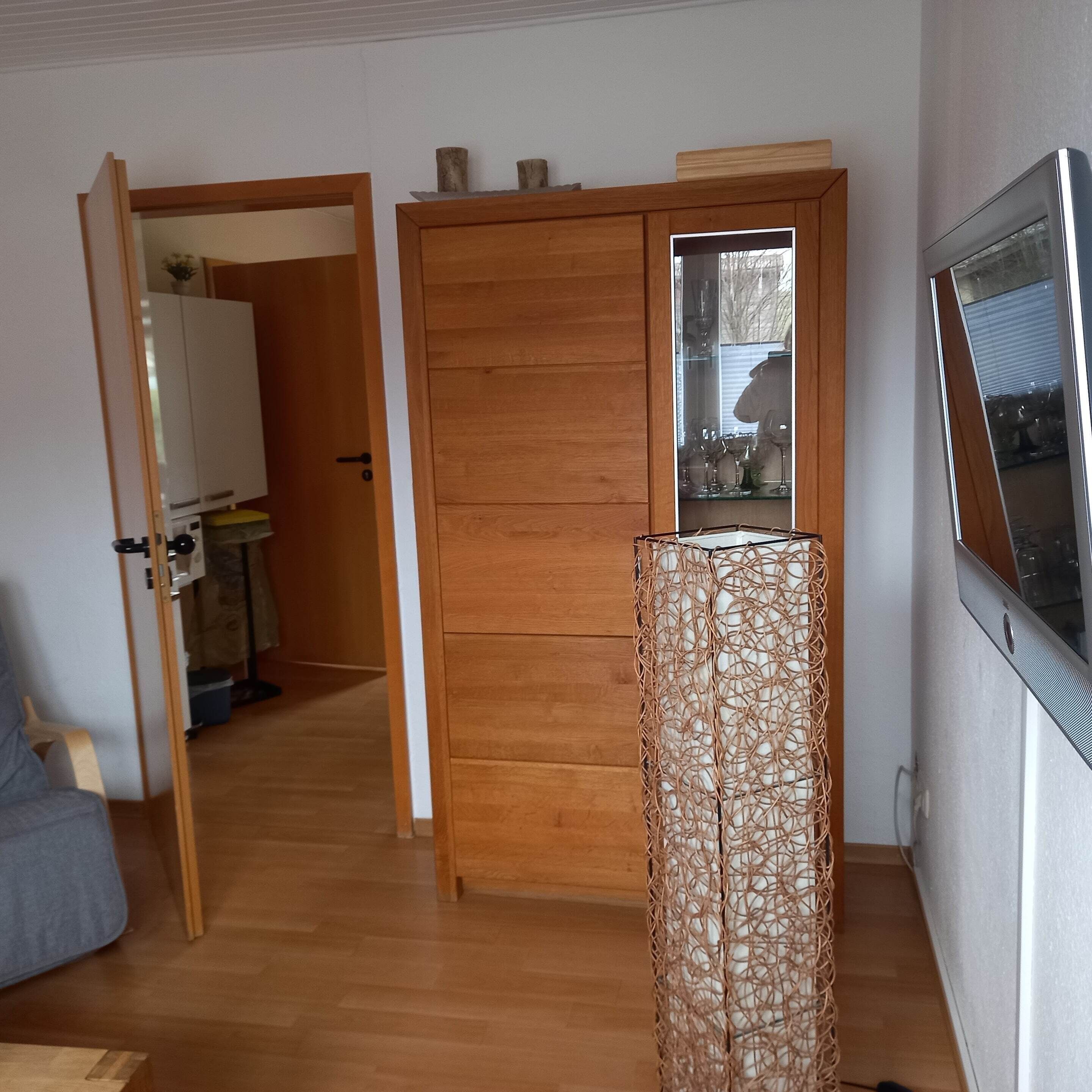 Una habitación con un armario de madera, un espejo y un televisor en la pared.