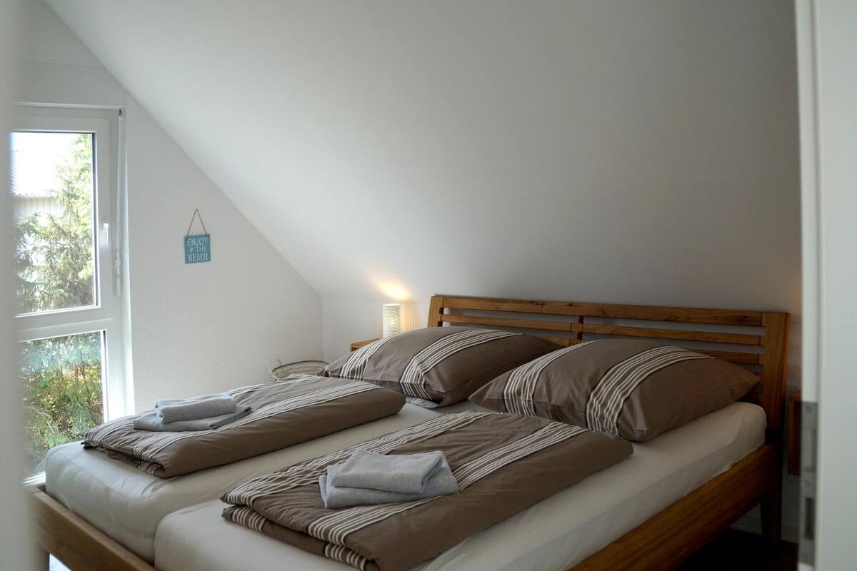 Una cama individual con cabecera de madera en una habitación con techos inclinados.