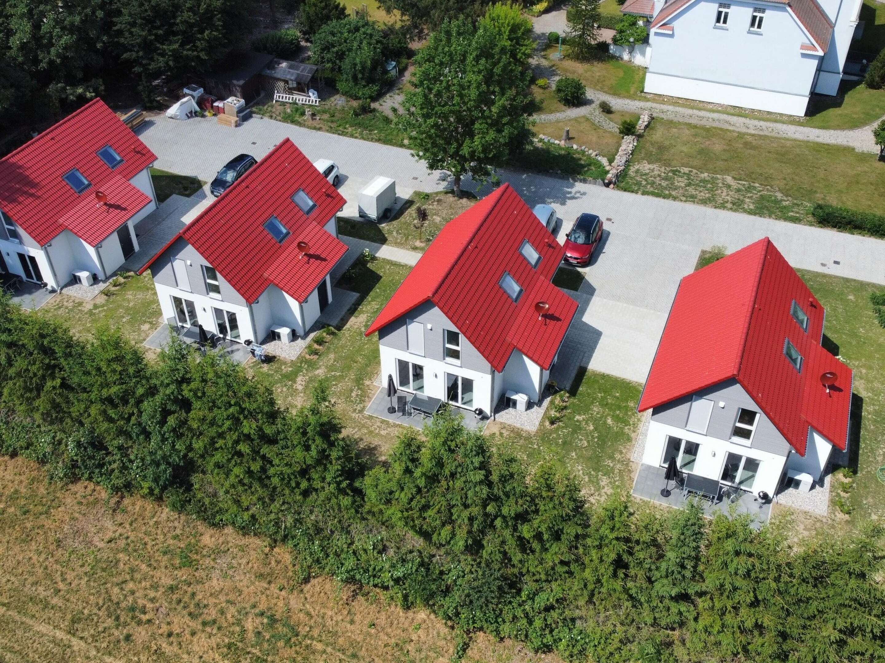 A cluster of modern houses with red roofs, arranged in a row along a street.