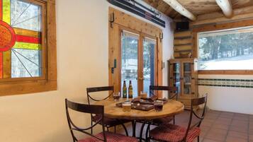 Un comedor acogedor con una mesa y sillas de madera, un ventanal de vitral y vistas a un paisaje nevado.
