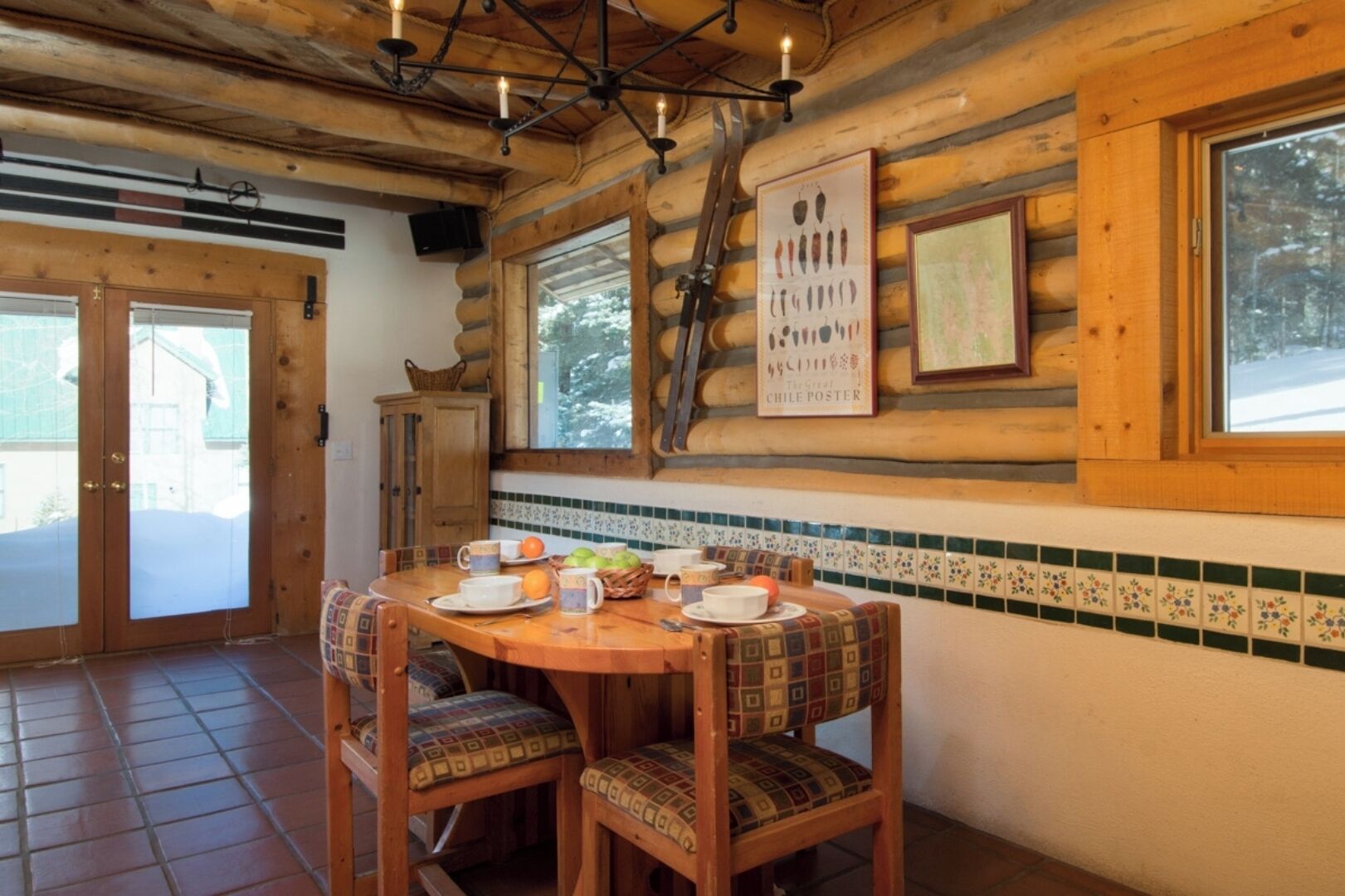 Un comedor de madera con una mesa redonda, sillas y un cartel de Chile en la pared.