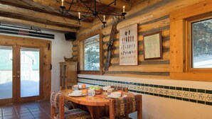 A wooden dining area with a round table, chairs, and a Chile poster on the wall. - Denton Cabin - Warm Log Cabin, close to Mountain Stream and Ski Return Trail (Taos Ski Valley)