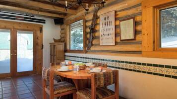 Un comedor de madera con una mesa redonda, sillas y un cartel de Chile en la pared.