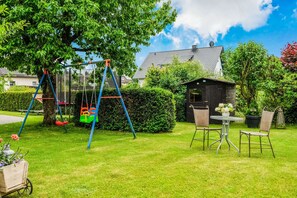 A backyard with a swing set, a small table with chairs, and a wooden shed. - Luxurious Apartment in Medebach Near Public Pool (Medebach)