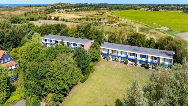 Ein Hotel mit zweigeschossigen Gebäuden, umgeben von Grünflächen und Feldern.