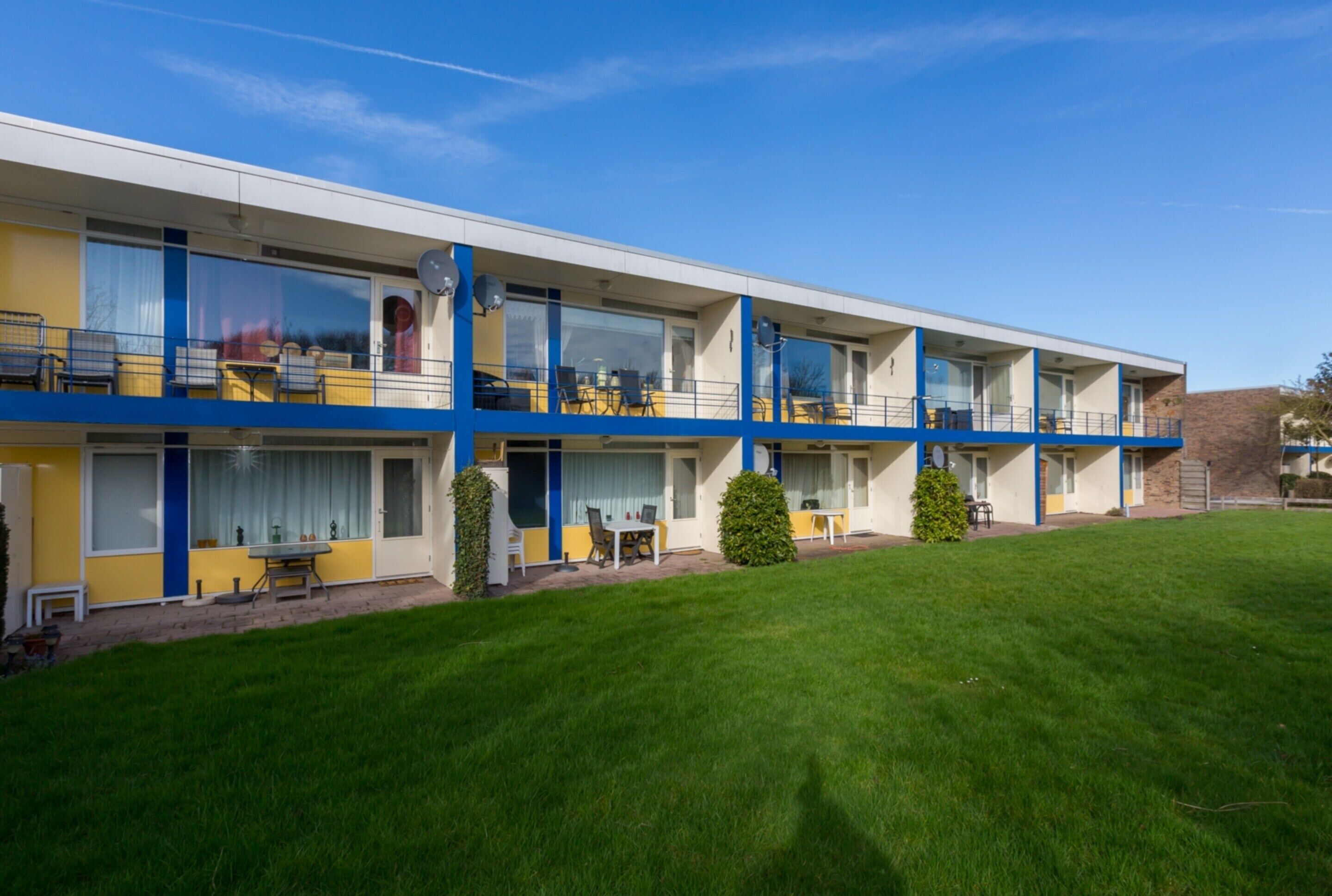 A modern motel with multiple balconies, each with outdoor seating.