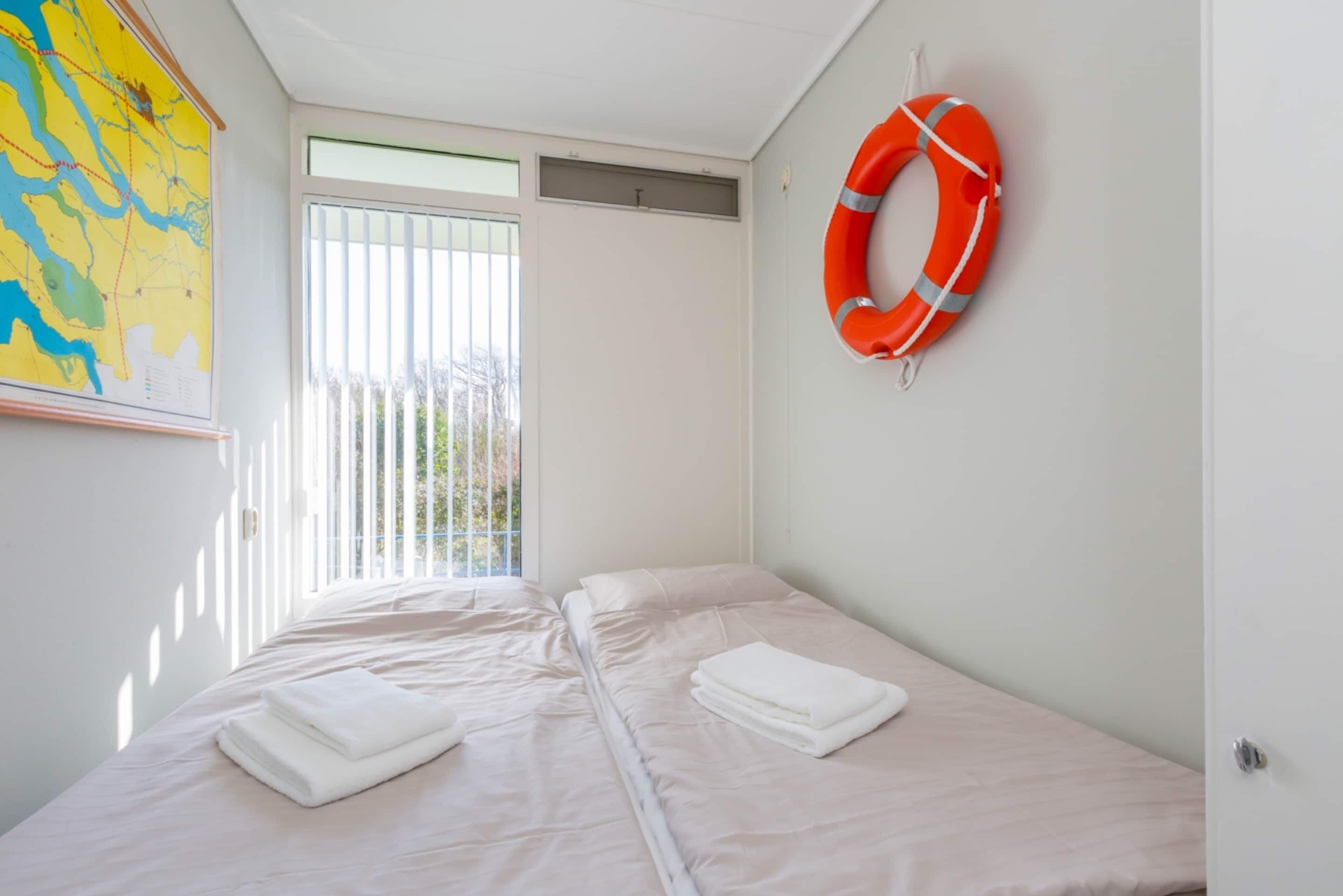 Een hotelkamer met twee bedden, een reddingsboei aan de muur en een kaart aan de muur.