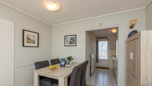 Een eetgedeelte met een houten tafel, grijs gestoffeerde stoelen en ingelijste foto's aan de muur.