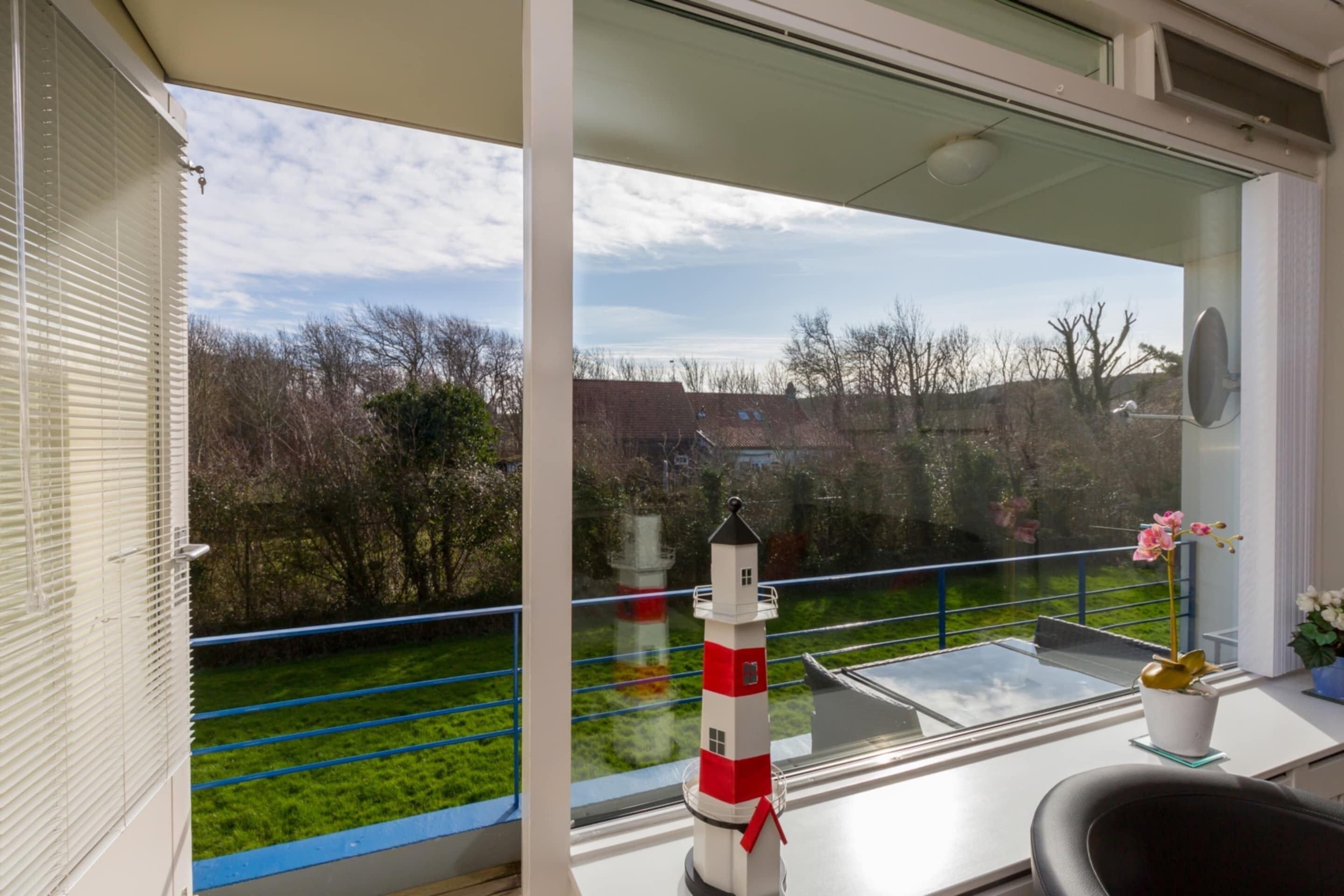 A balcony with a view of a green lawn and a red and white lighthouse model.