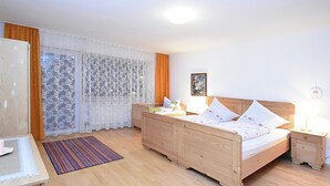 A bedroom with a wooden bed, a bedside table, a nightstand, a desk, and a chair. - Welcoming Chalet Near Forest in Rohrnbach (Roehrnbach)