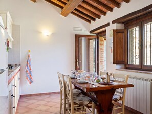 A dining area with a wooden table, chairs, and a window with a view. - Modern Holiday Home in Pietrafitta Umbria With Garden (Piegaro)