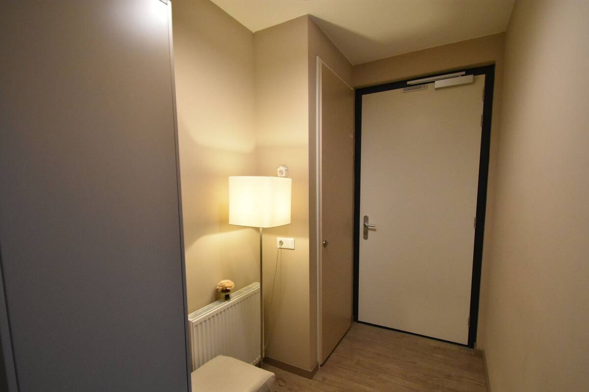 A narrow hallway with a radiator, a small bench, and a door with a towel hanging on the handle.