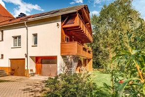 Ett tvåvåningshus med en träbalkong, ett garage och en välskött trädgård.