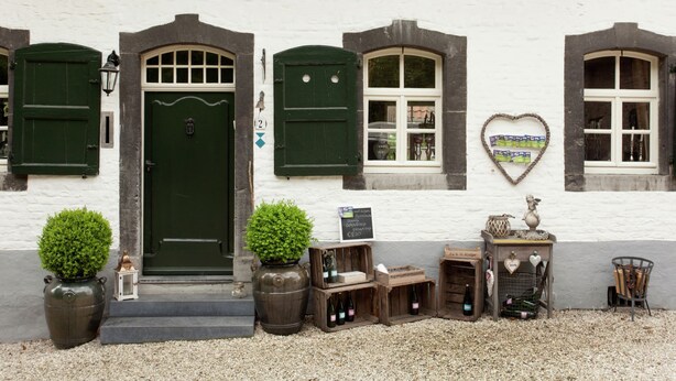 A white building with green shutters, a green door, and a heart-shaped sign on the wall. - Stunning Holiday Home Near Forest in Slenaken (Slenaken)