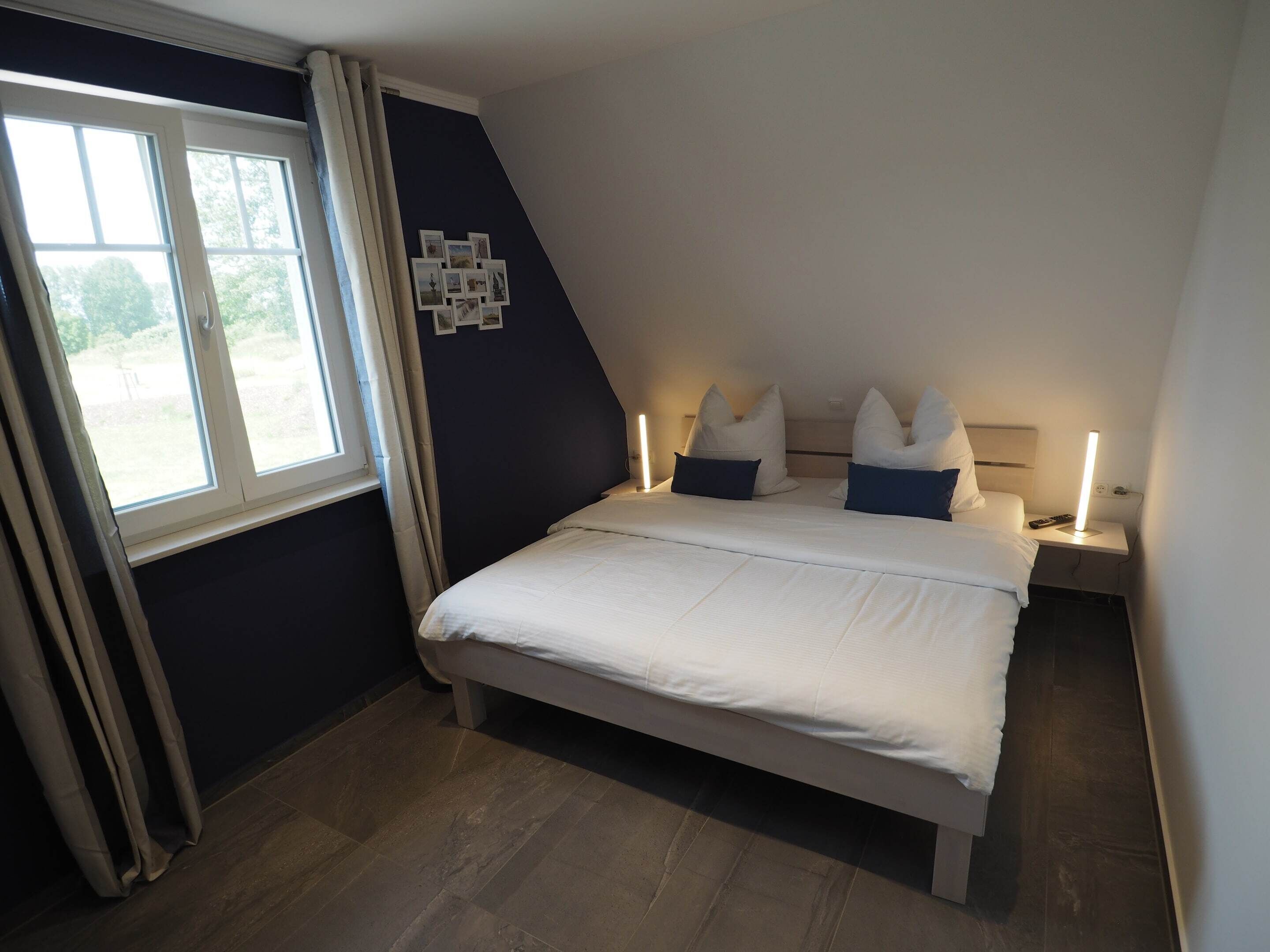 A bedroom with a large bed, a window, and a wall-mounted picture frame.