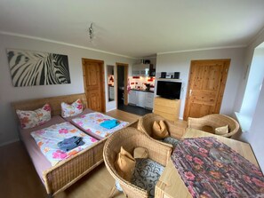 A room with a bed, two wicker chairs, a small table, and a TV. - Modern Apartment in Bastorf Near Sea (Bastorf)