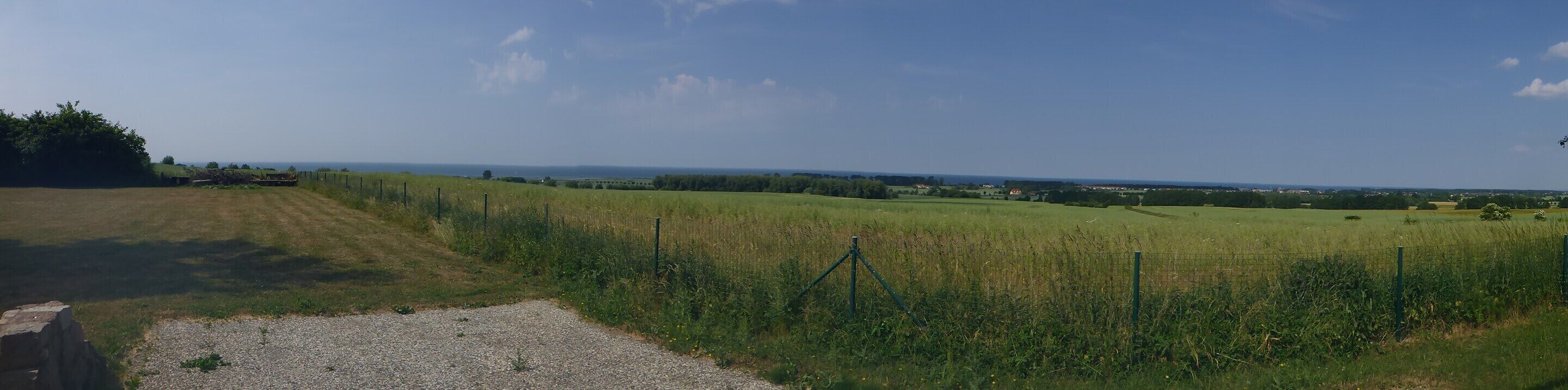 A rural landscape with fields, a gravel path, and a fence.