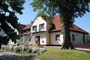 A two-story house with a red-tiled roof, a balcony, and a staircase leading to the entrance. - Snug Apartment in Kropelin Germany (Kroepelin)