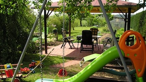 A children's play area with a swing set, a slide, and a small table with chairs. - Snug Apartment in Kropelin Germany (Kroepelin)