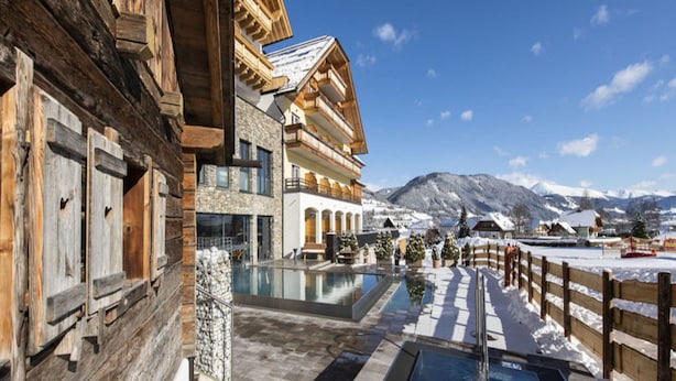 A wooden building with a pool area and a view of snow-covered mountains.
