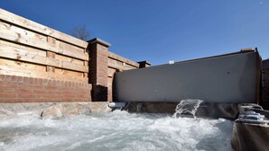 Ein Whirlpool, in den Wasser fließt, umgeben von Holzwänden und einer Ziegelstruktur.