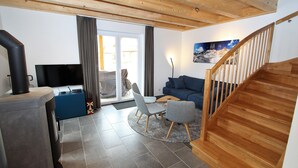 Ein modernes Wohnzimmer mit Kamin, Fernseher, Sofa und Treppe.